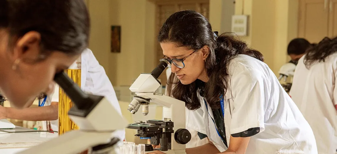 GITAM student researcher examining a sample under a microscope